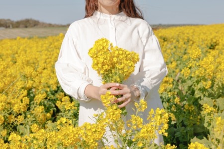 黄色い花を持って立つ女性
